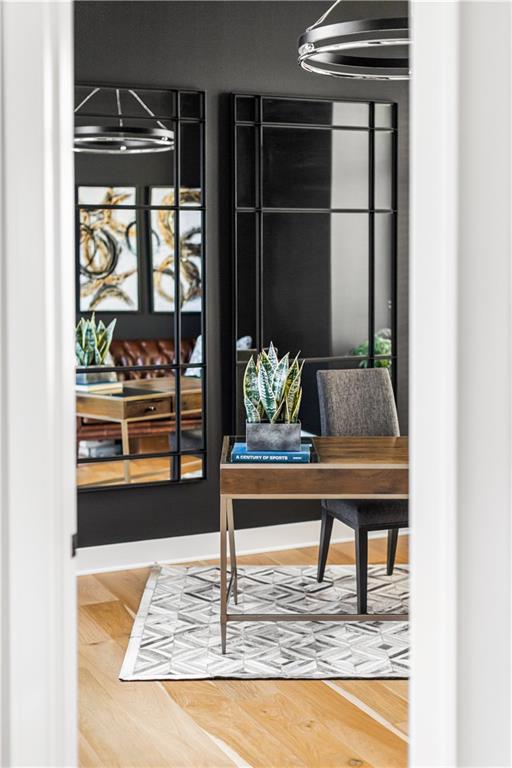Home office with a wood desk, gray chair, geometric rug, and black-framed glass panels.
