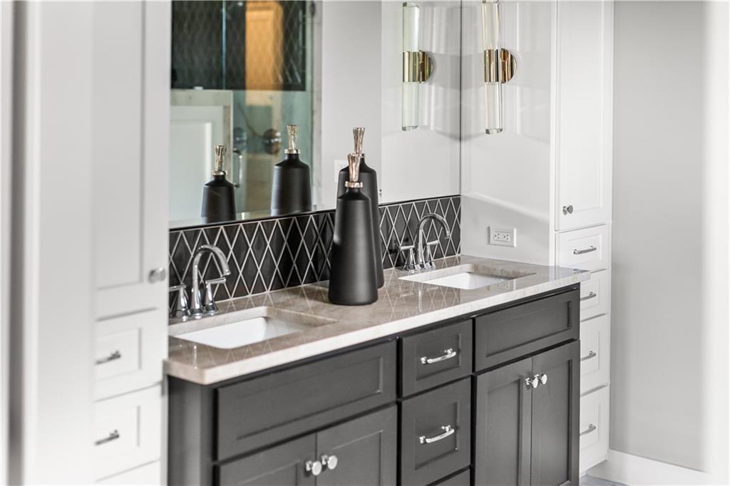 Bathroom vanity with two sinks, a dark gray cabinet, and a geometric black backsplash.