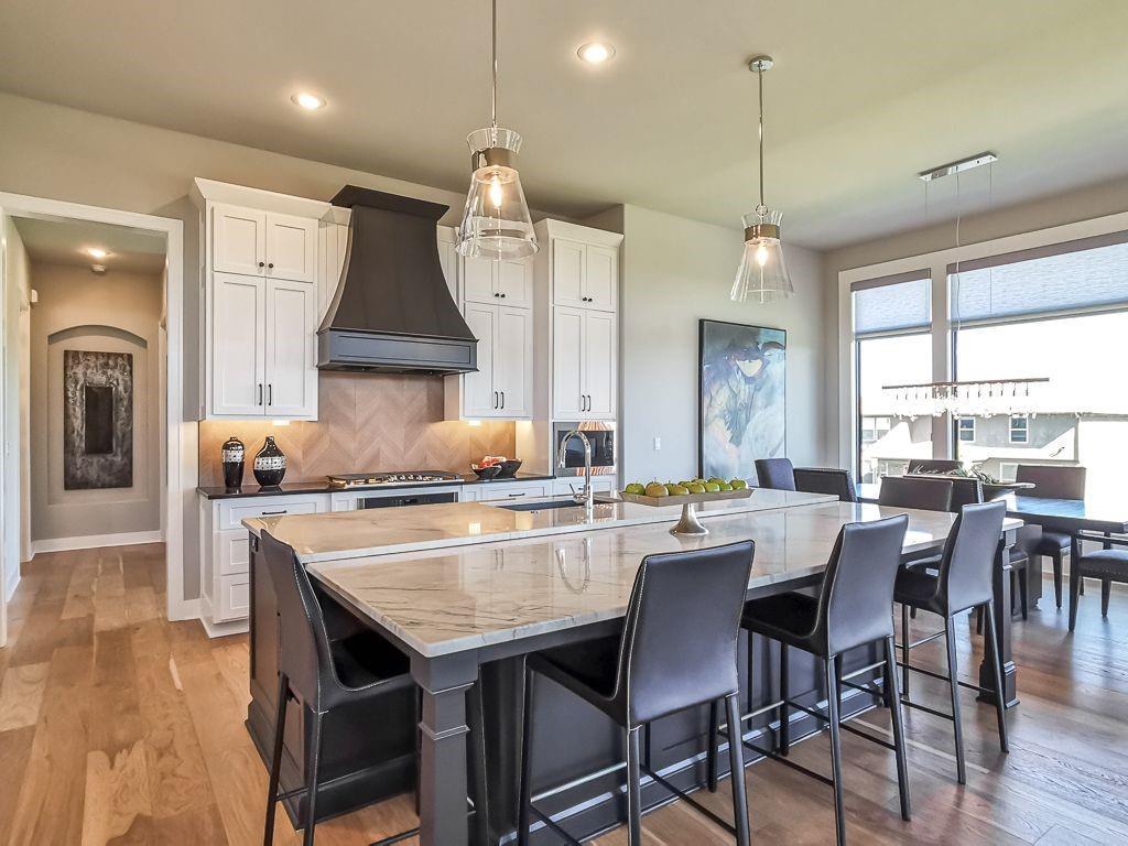 Kitchen with a marble island, white cabinetry, and bar seating beside a windowed dining area.