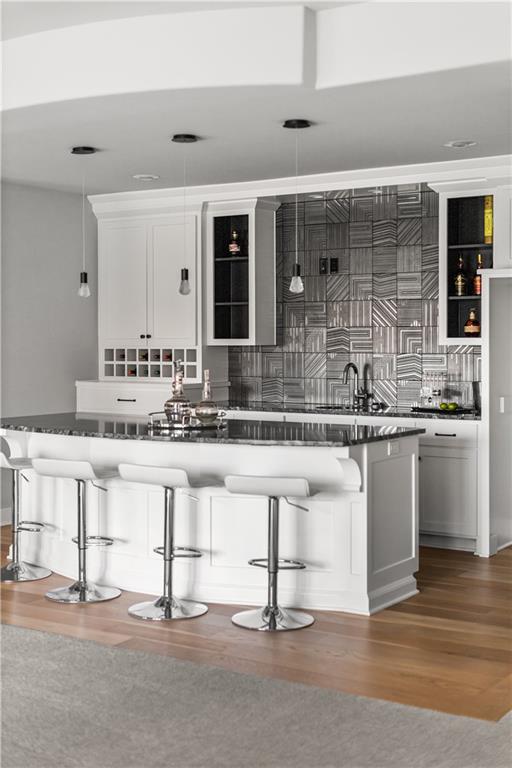 Modern kitchen with a large white island, bar stools, and a geometric gray tile backsplash.