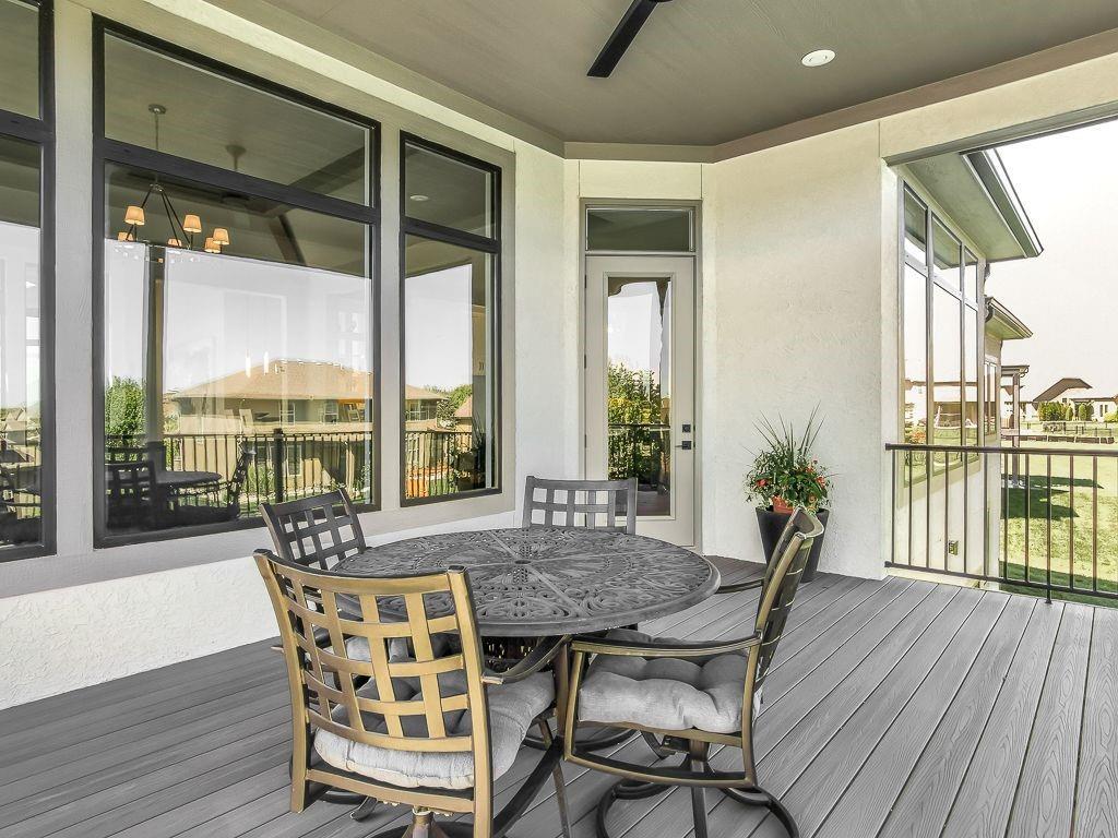 Covered patio with a round dining set, gray decking, and large windows overlooking the backyard.