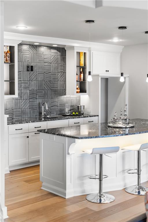 Modern kitchen with a marble-topped island, white cabinetry, and geometric gray tile backsplash.