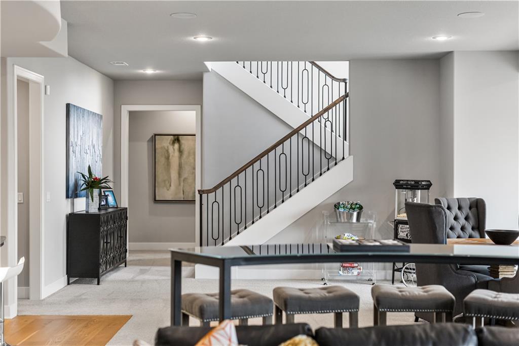 Open-plan dining and living area with a carpeted staircase and black metal railing.