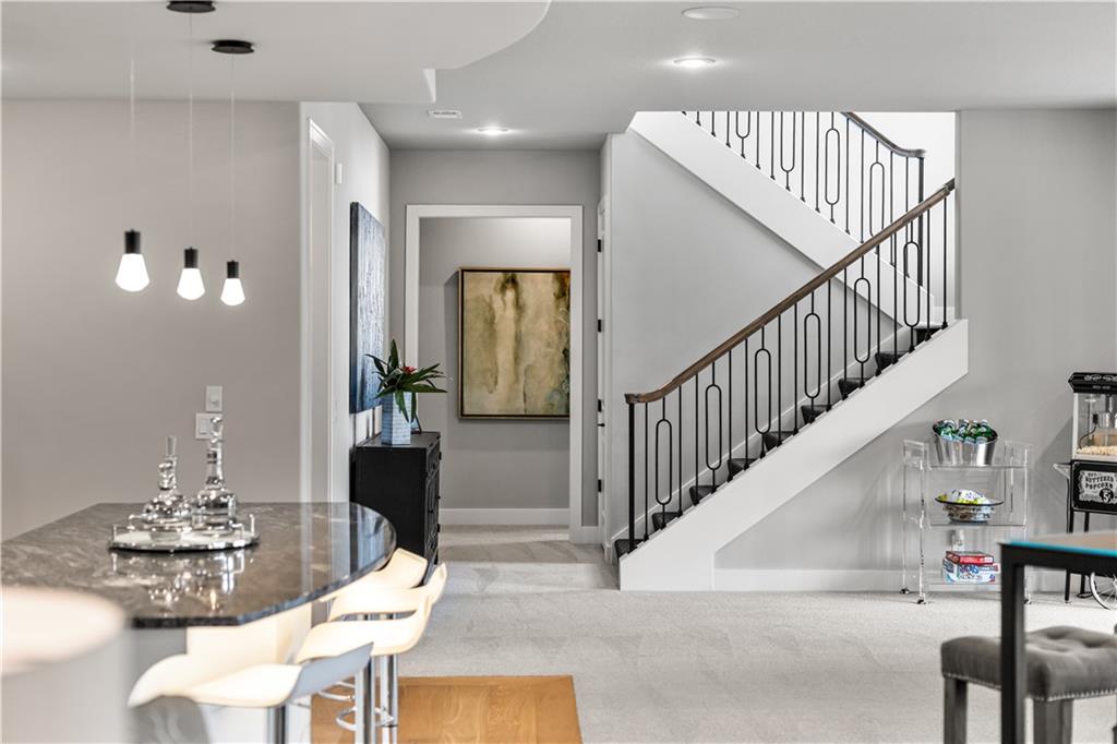 Open foyer with a curved stone breakfast bar and staircase with black metal balusters.