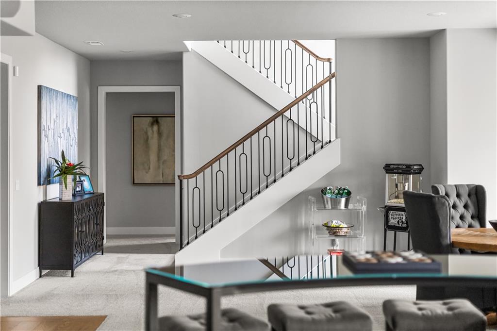 Living room with a carpeted staircase, black metal balusters, and a wood handrail.