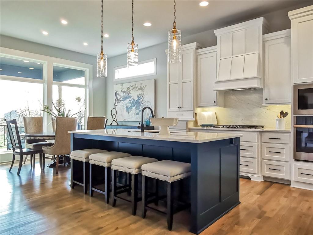 Kitchen with a navy island, white cabinetry, pendant lights, and an adjoining dining area.