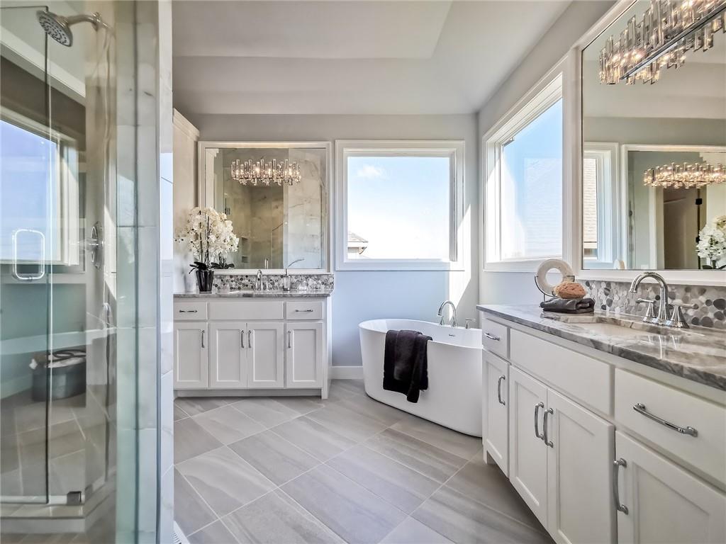 Bright bathroom with a freestanding tub, glass shower, and long double vanity.