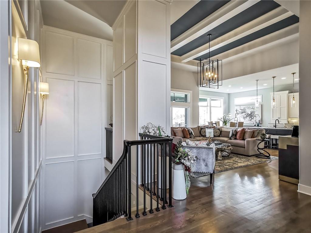 Open living room with a coffered ceiling, neutral furnishings, and a staircase.