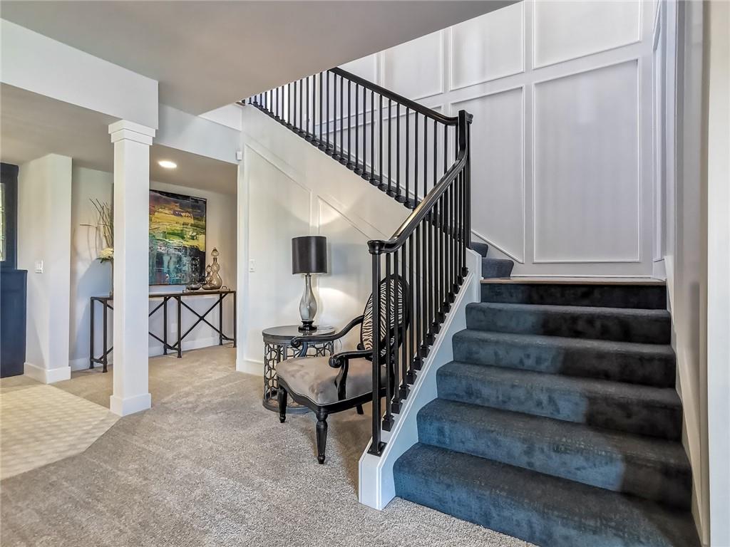 Foyer with a carpeted staircase, black railing, and sitting area.