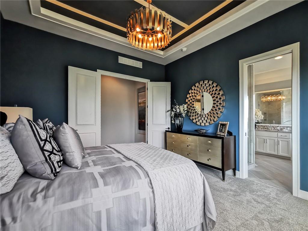 Staged bedroom with a gray bed, dark blue walls, and an adjoining bathroom.
