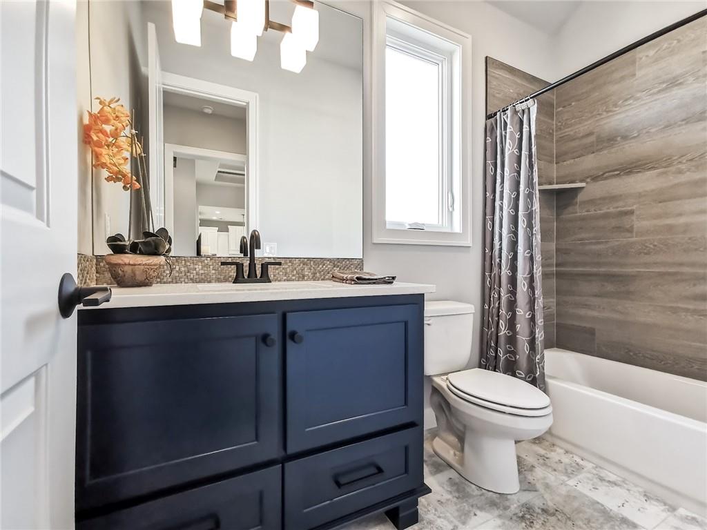 Bathroom with a navy vanity, white countertop, and gray-tiled tub surround.