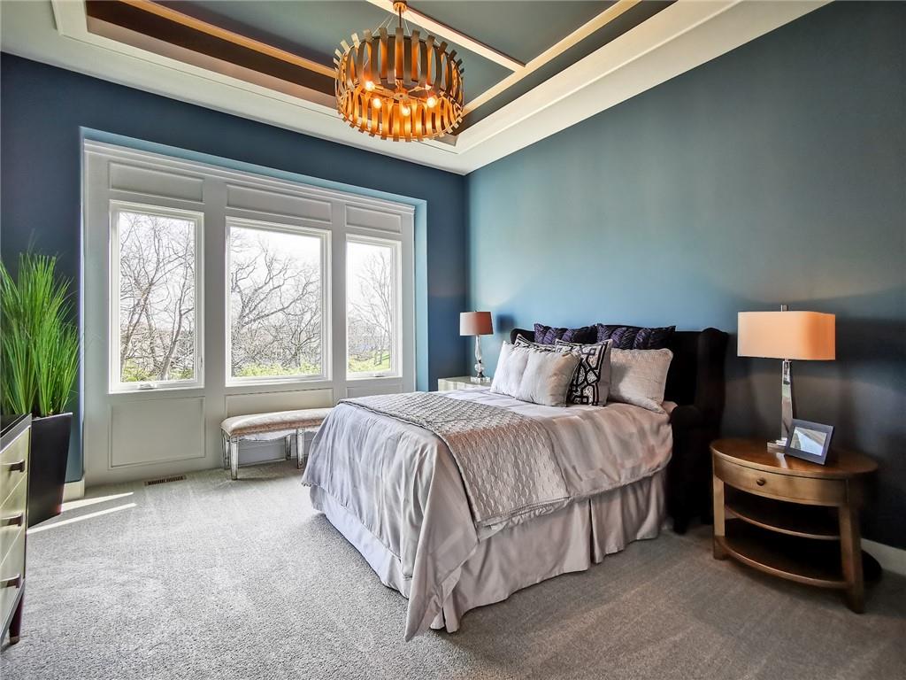 Staged bedroom with a large bed, blue walls, and three tall windows.