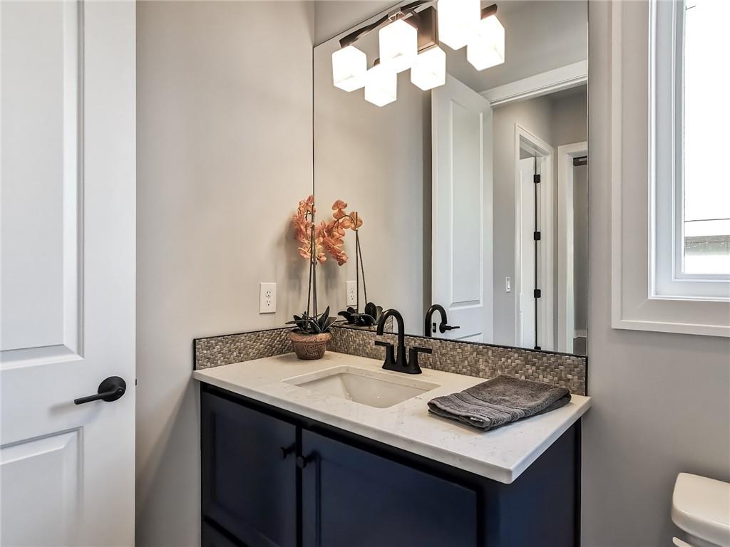 Bathroom vanity with a dark blue cabinet, white countertop, and orchid beside a window.