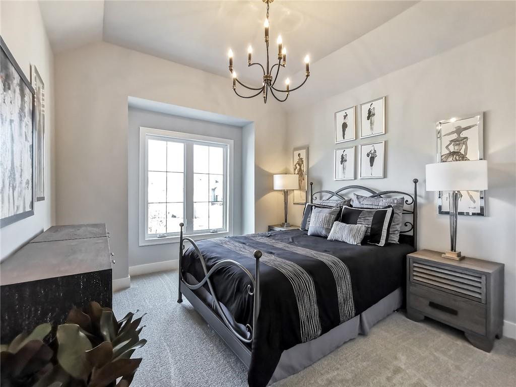 Bedroom with a black metal bed, charcoal bedding, and a chandelier beneath a vaulted ceiling.