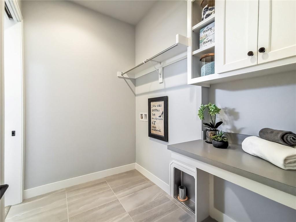 Laundry room with gray tile flooring, a folding counter, upper cabinets, and a hanging rod.