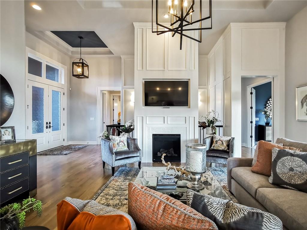 Living room with a tall paneled fireplace wall, mounted TV, and arranged seating.