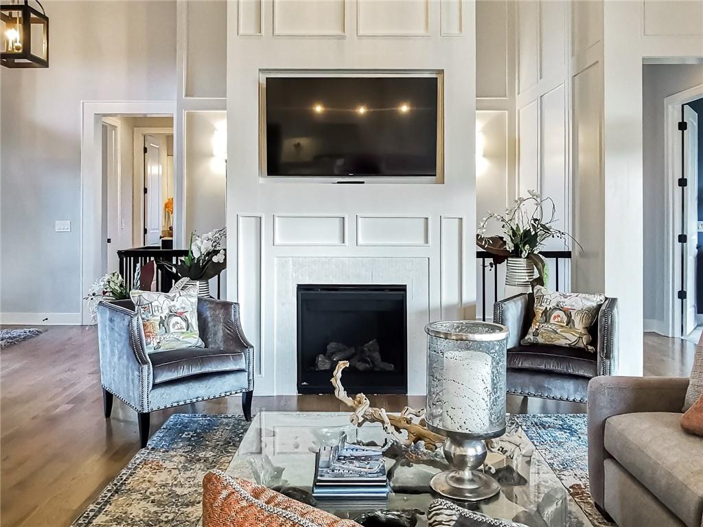 Living room with a paneled fireplace wall, mounted television, and two upholstered chairs.