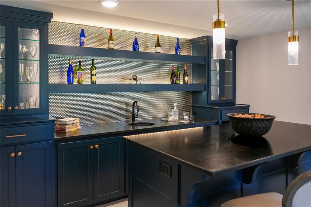 Wet bar with navy cabinetry, mirrored backsplash, and a large black island.