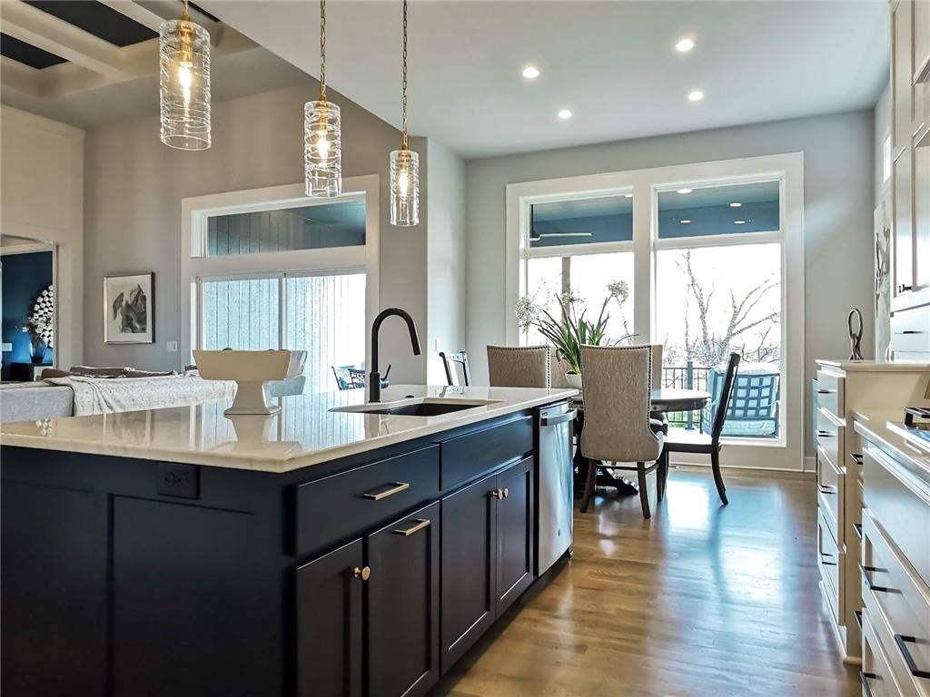 Kitchen with a navy island, white countertops, pendant lights, and a dining area by large windows.
