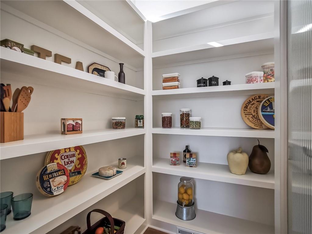 Pantry with white built-in shelves, neatly arranged jars, dishes, and kitchen utensils.