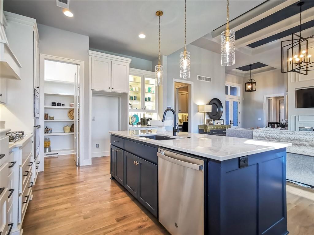 Kitchen with a navy island, white counters, pendant lights, and open shelving.