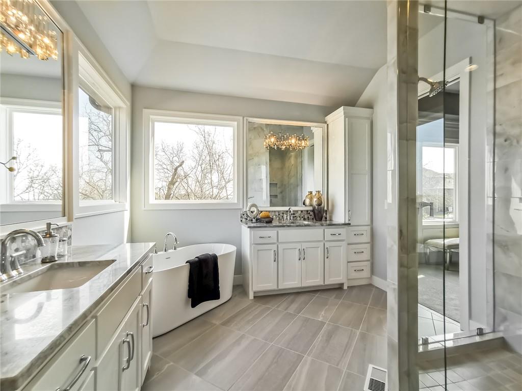 Bright bathroom with a freestanding tub, double vanity, and glass-enclosed shower.