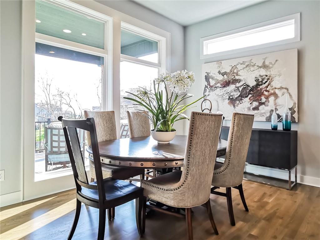 Dining room with a round table, upholstered chairs, abstract artwork, and tall windows.