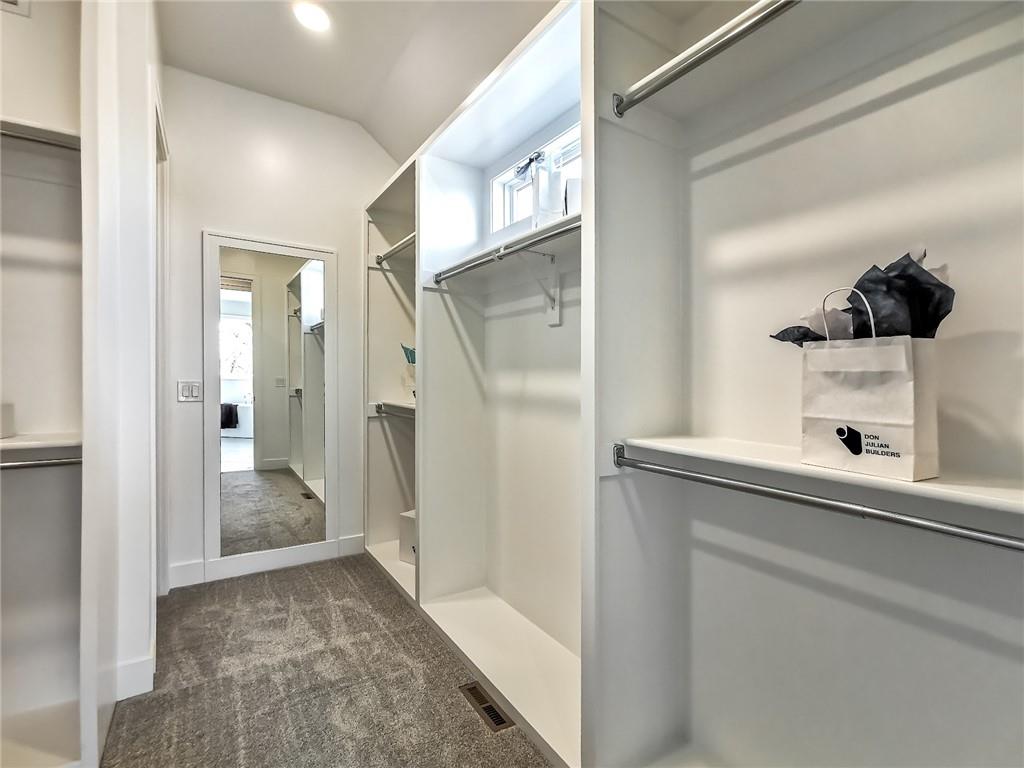Walk-in closet with gray carpet, white built-in shelving, and a full-length mirror.