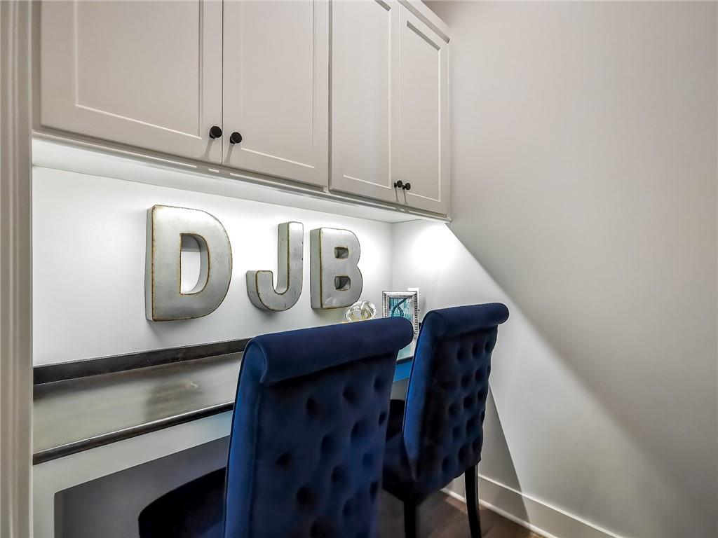 Built-in desk nook with white cabinetry, a dark countertop, and two navy chairs.