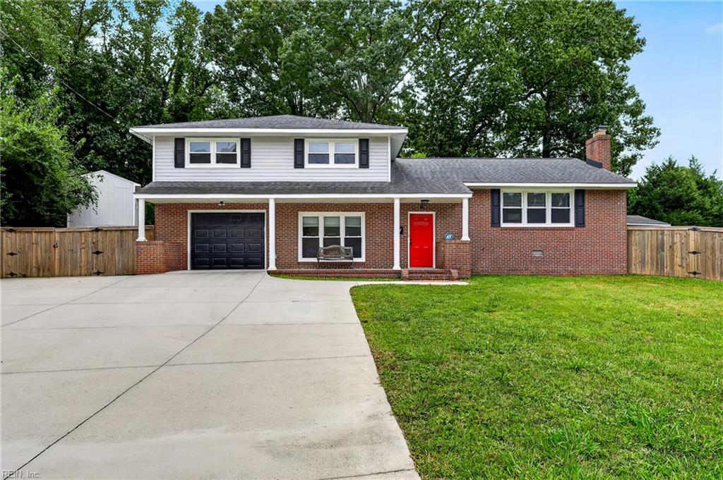 Brick two-story home with a bright red front door, black garage door, and broad driveway.