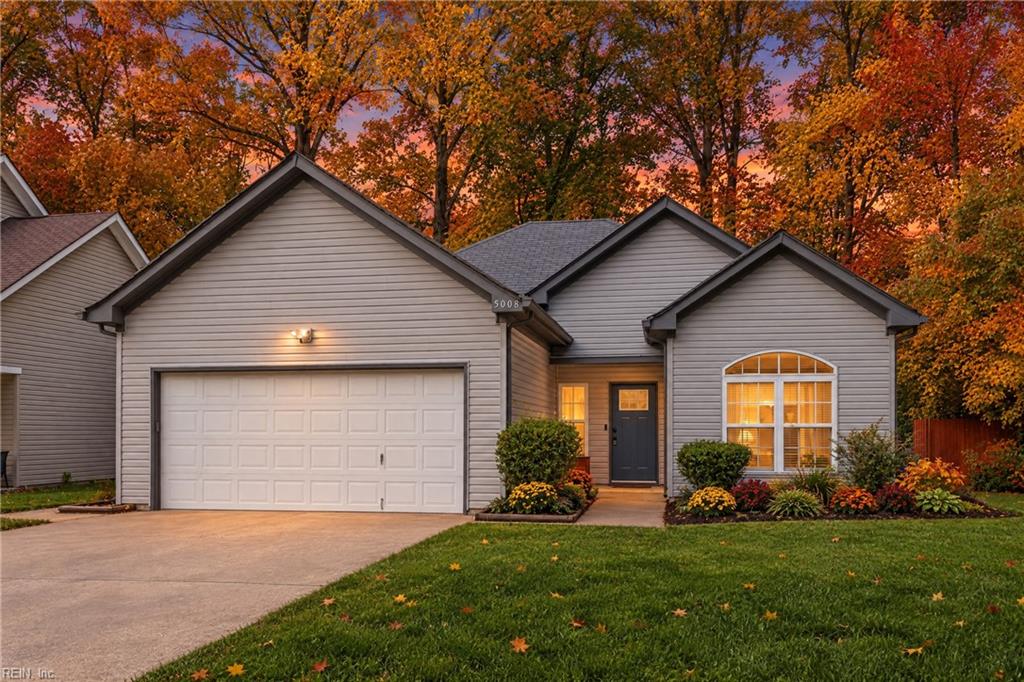 Gray-sided house with a two-car garage and autumn trees at dusk.