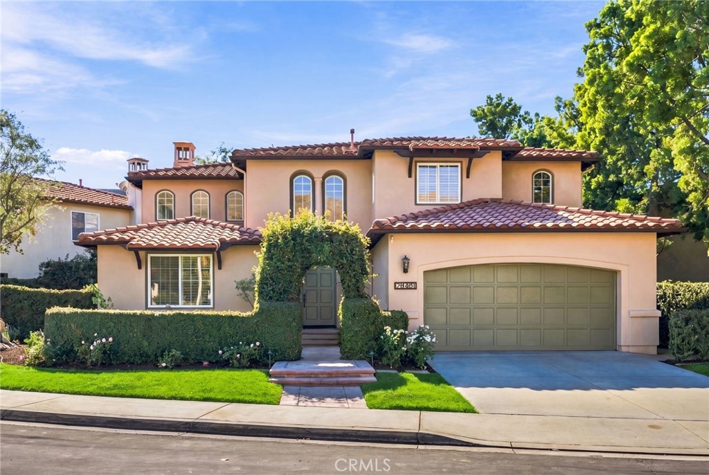 Two-story stucco home with terracotta tile roofs, a wide garage, and landscaped front yard.