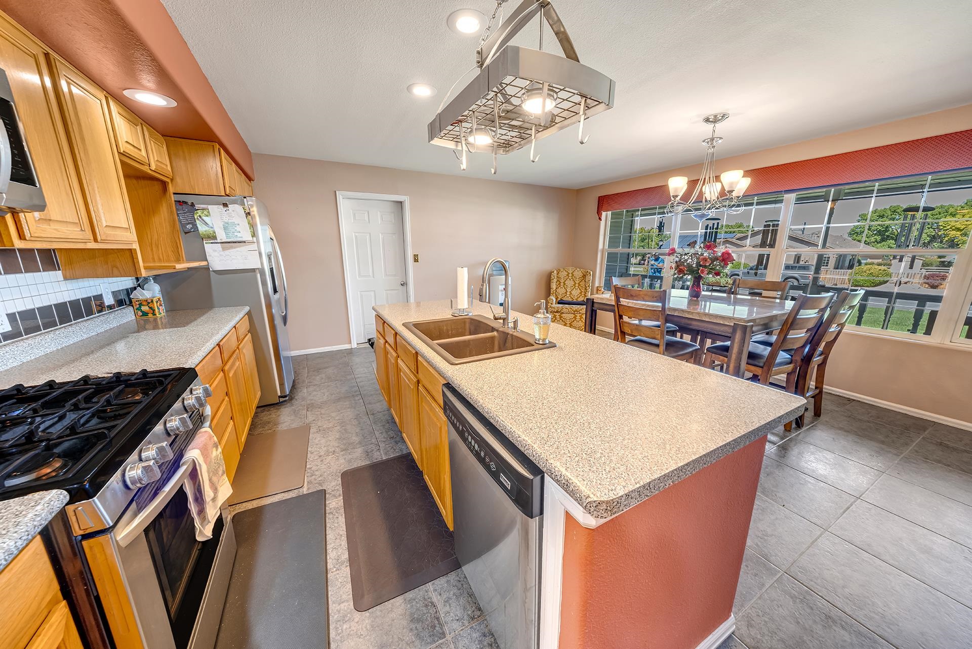 Kitchen with a large granite island and dining area beside broad windows.