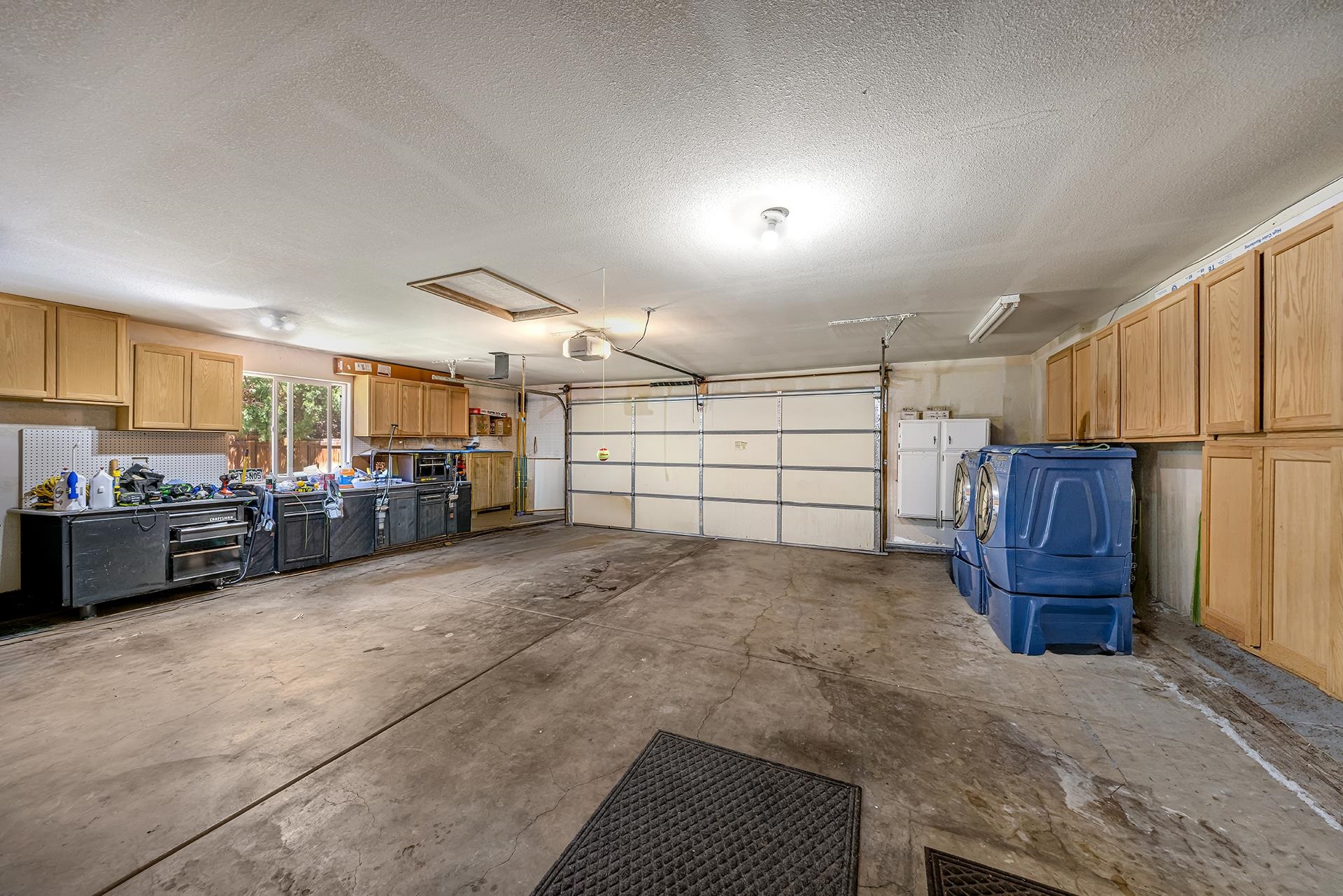 Garage with extensive wooden cabinets, a workbench, and a blue washer and dryer.