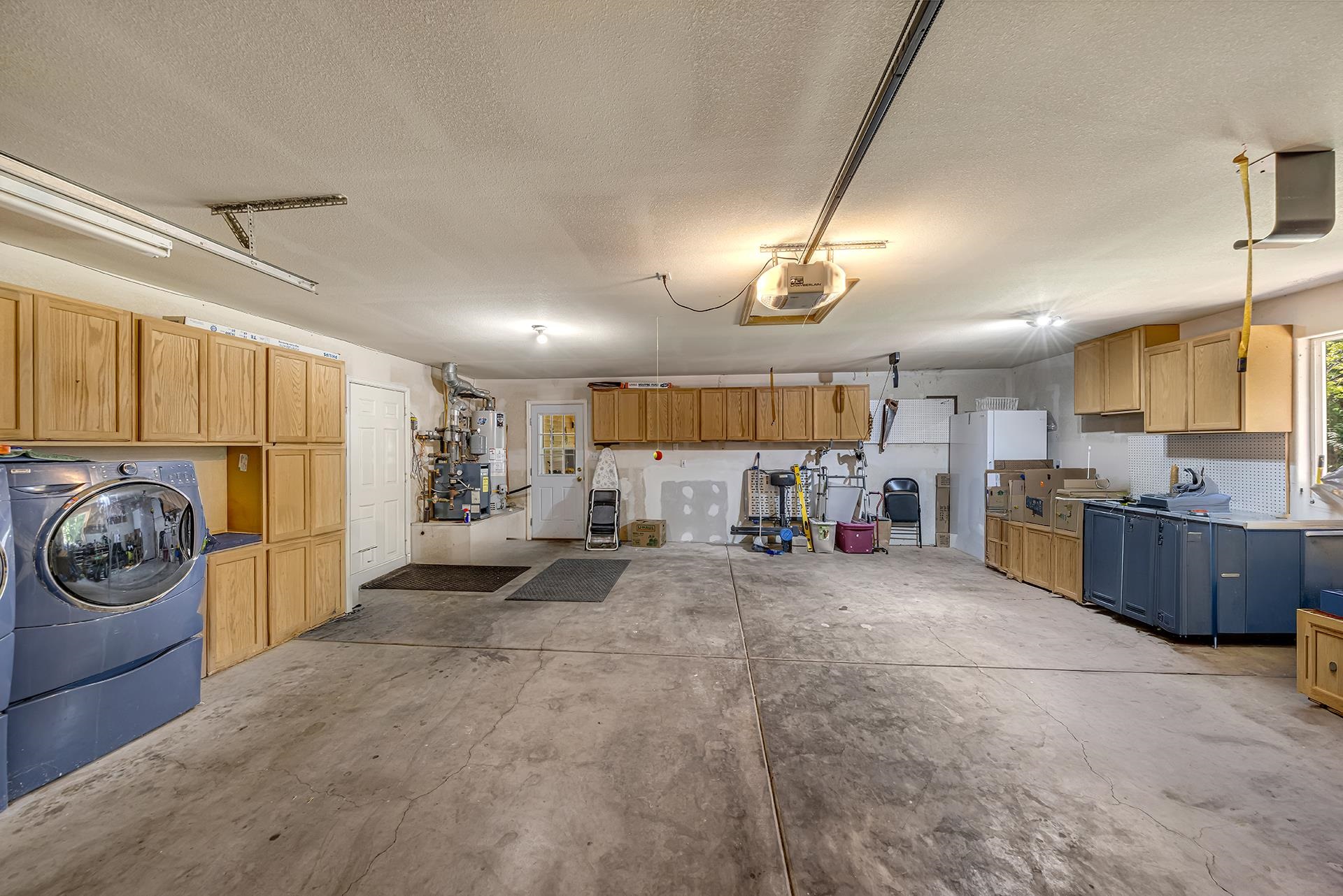 Spacious garage with wood cabinets, washer and dryer, and a broad concrete floor.