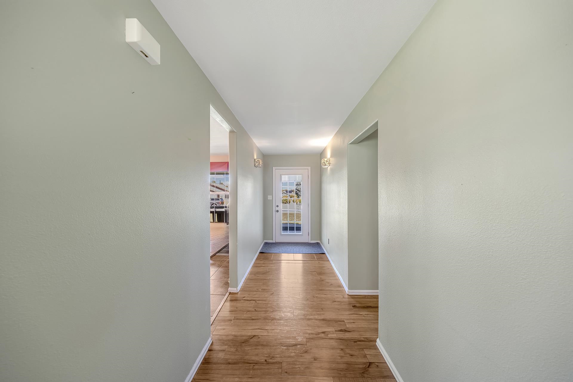Entry hallway with wood-look flooring, wall sconces, and a glass-panel front door.