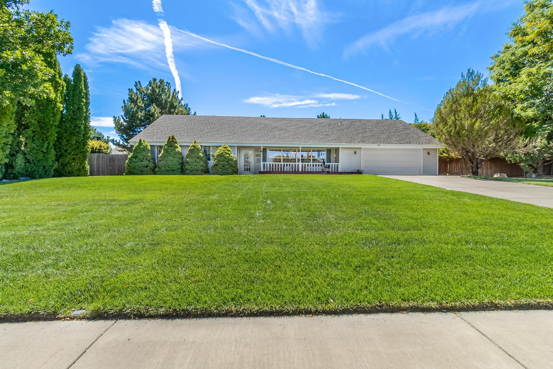 Single-story home with a covered porch, two-car garage, and broad green lawn.