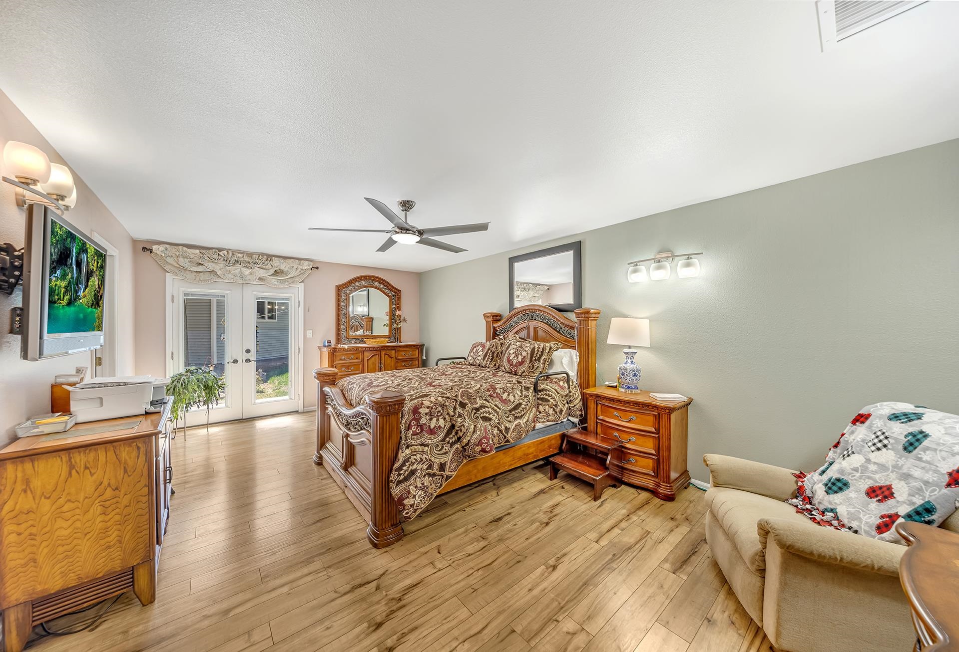 Bedroom with an ornate wooden bed, matching dresser, and glass patio doors.