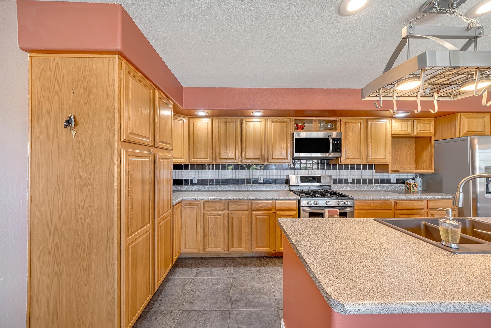 Kitchen with oak cabinets, stainless steel appliances, and a speckled island countertop with a double sink.