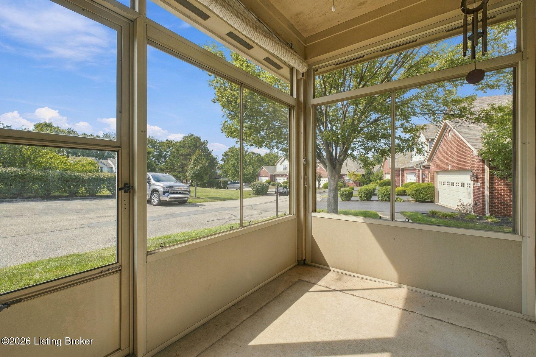 Enclosed sunroom with expansive windows, a wood ceiling, and views of a leafy residential street.