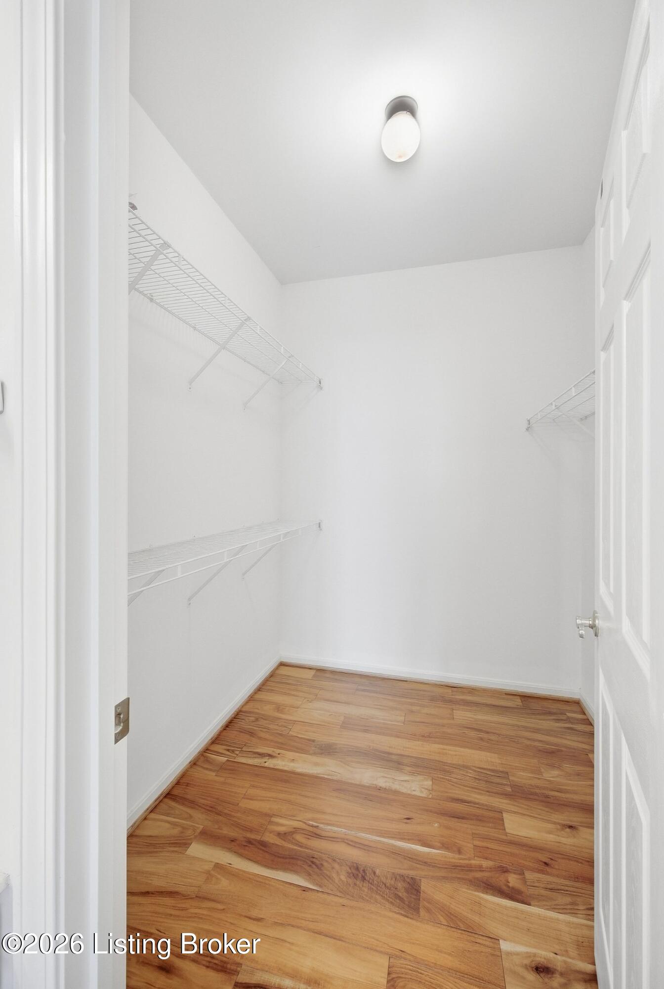Walk-in closet with white wire shelves and hardwood flooring.