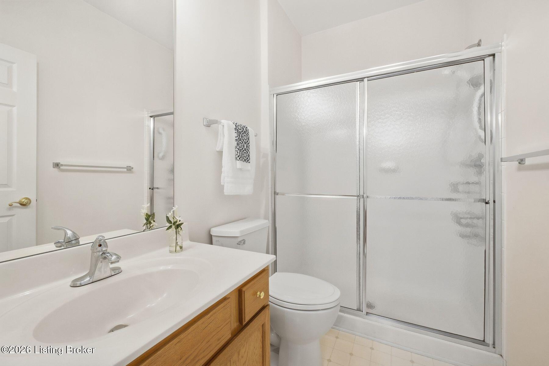 Bathroom with a wood vanity, large mirror, and frosted-glass sliding shower enclosure.