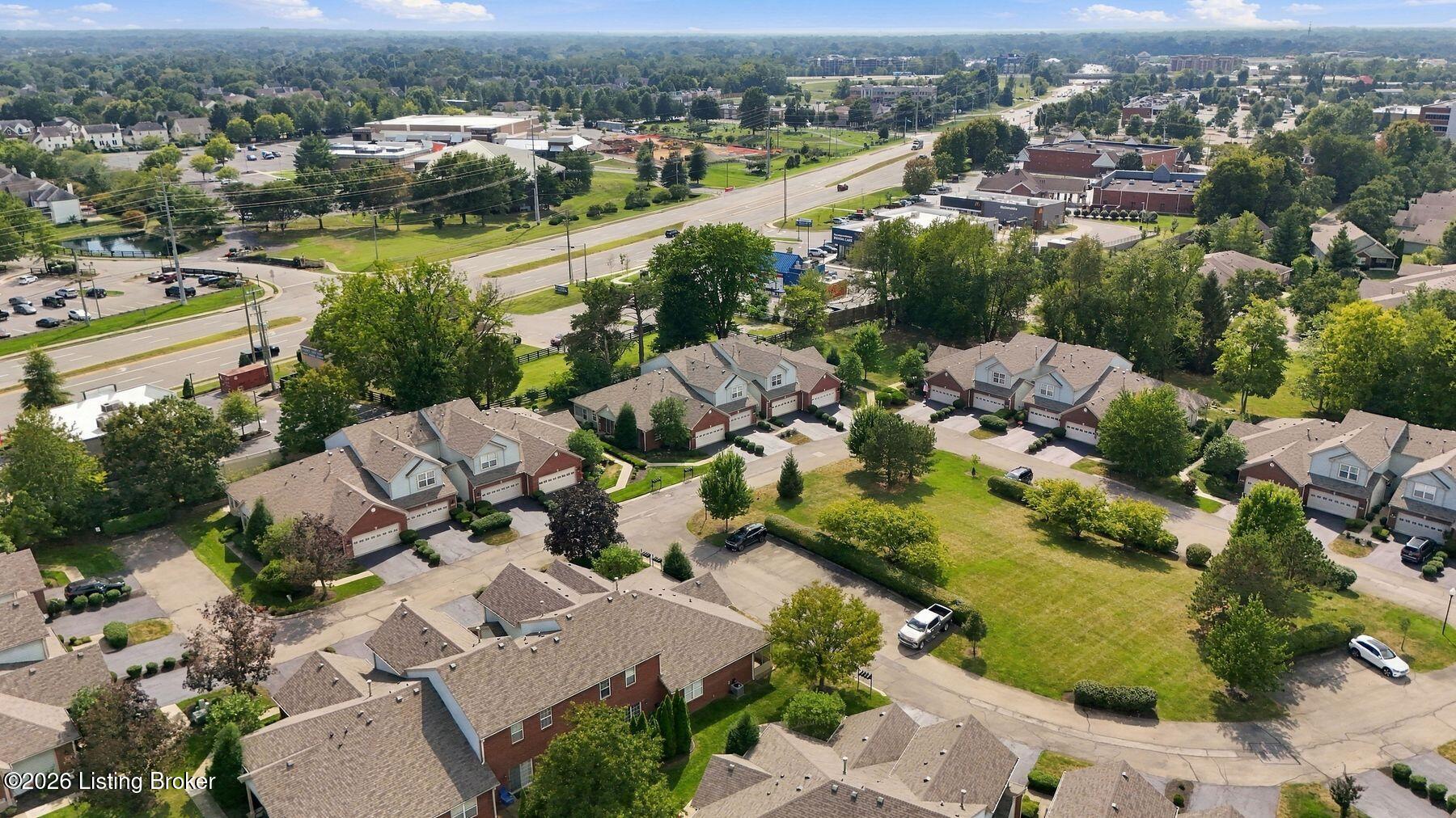 Aerial view of townhomes and surrounding neighborhood beside a major road.