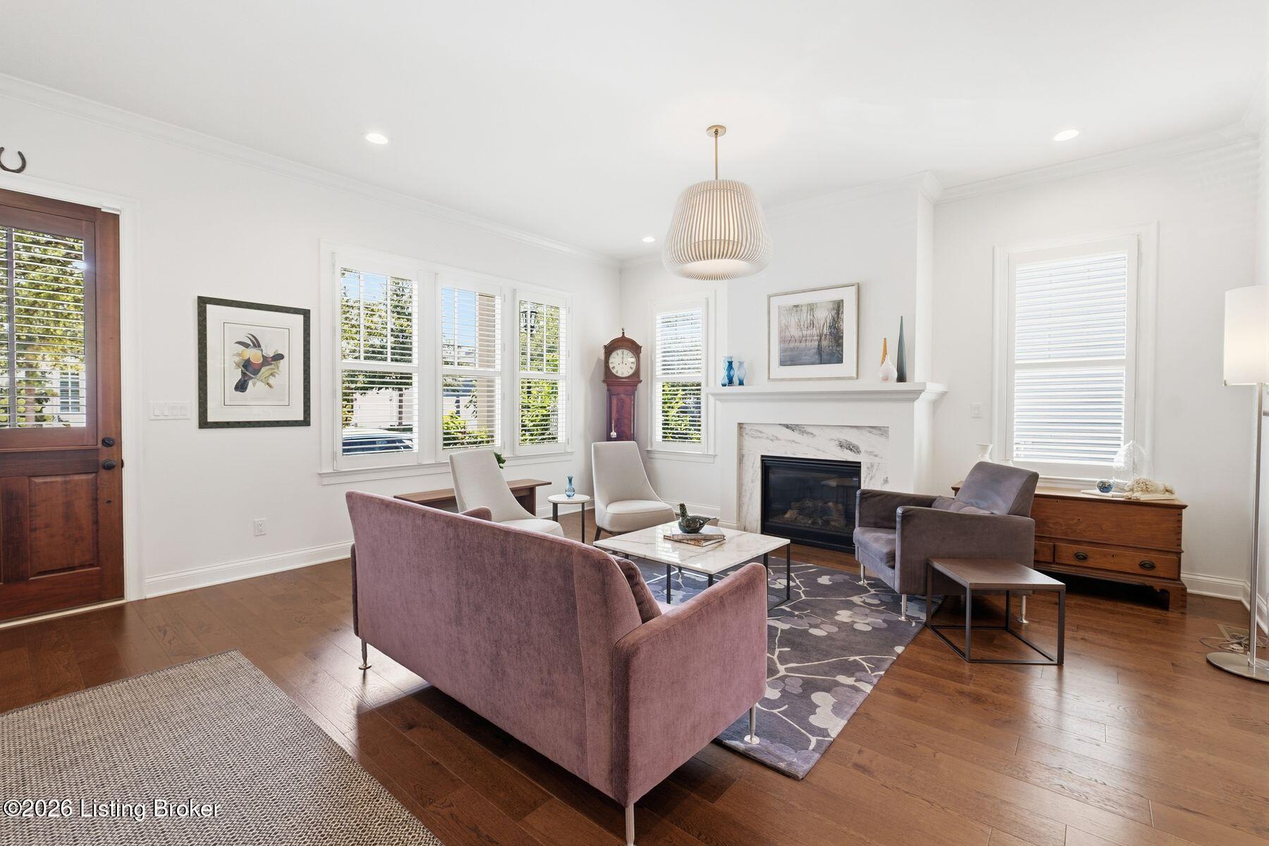 Furnished living room with a marble fireplace, shuttered windows, and mauve seating.