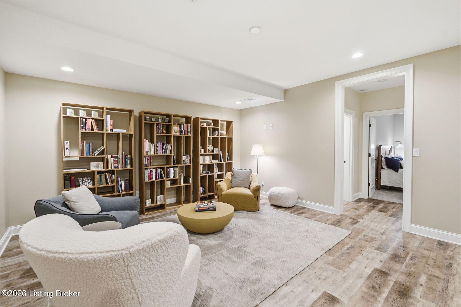 Furnished sitting room with wall-length bookcases and a doorway to a bedroom.