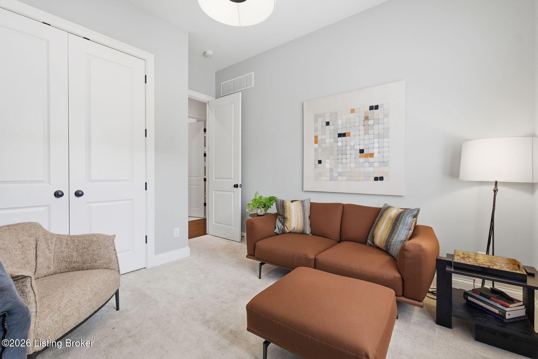 Living room with a rust-colored sofa, matching ottoman, and abstract wall art.