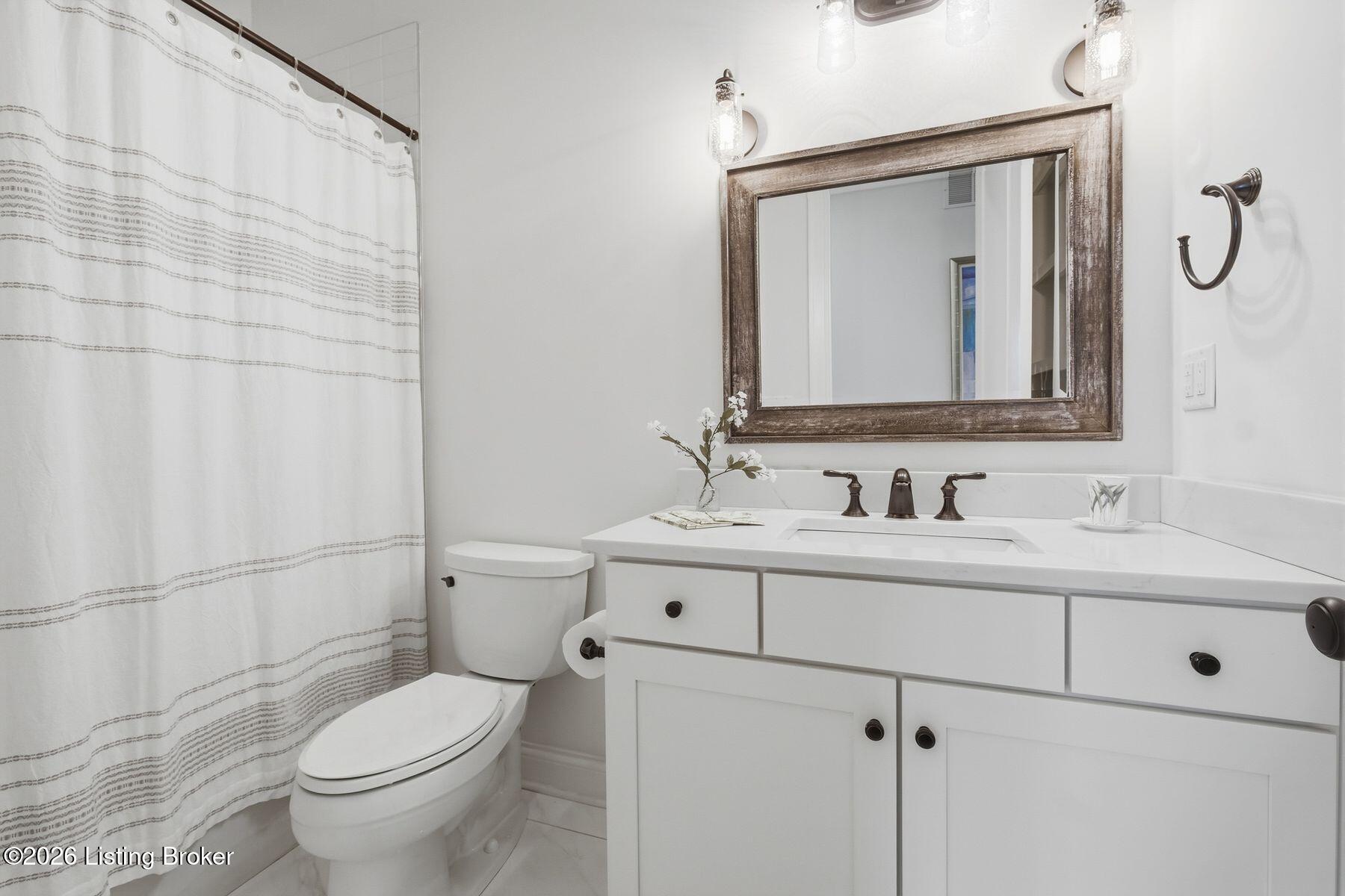 Bathroom with a white vanity, framed mirror, and striped shower curtain.