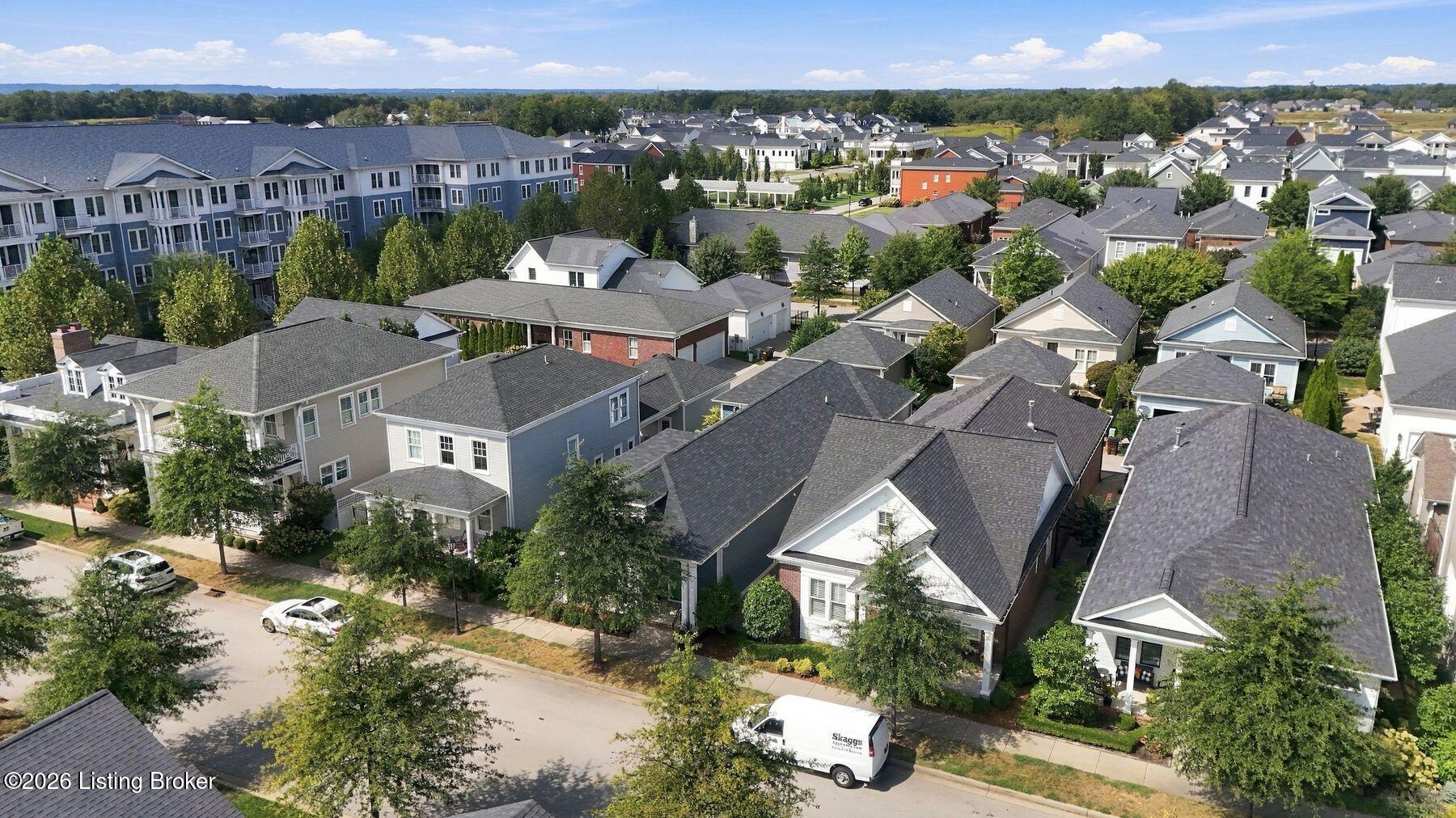 Aerial view of a residential neighborhood with closely spaced homes, mature trees, and an apartment building.