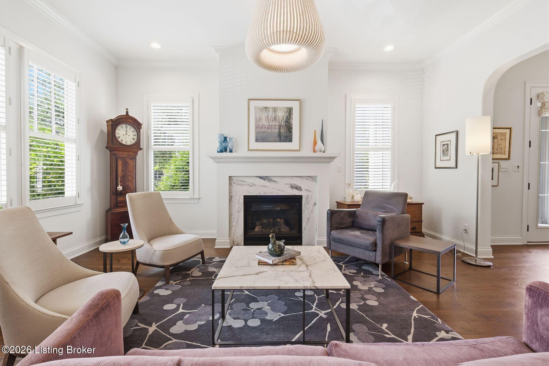Living room with a marble-surround fireplace, shuttered windows, and contemporary seating.