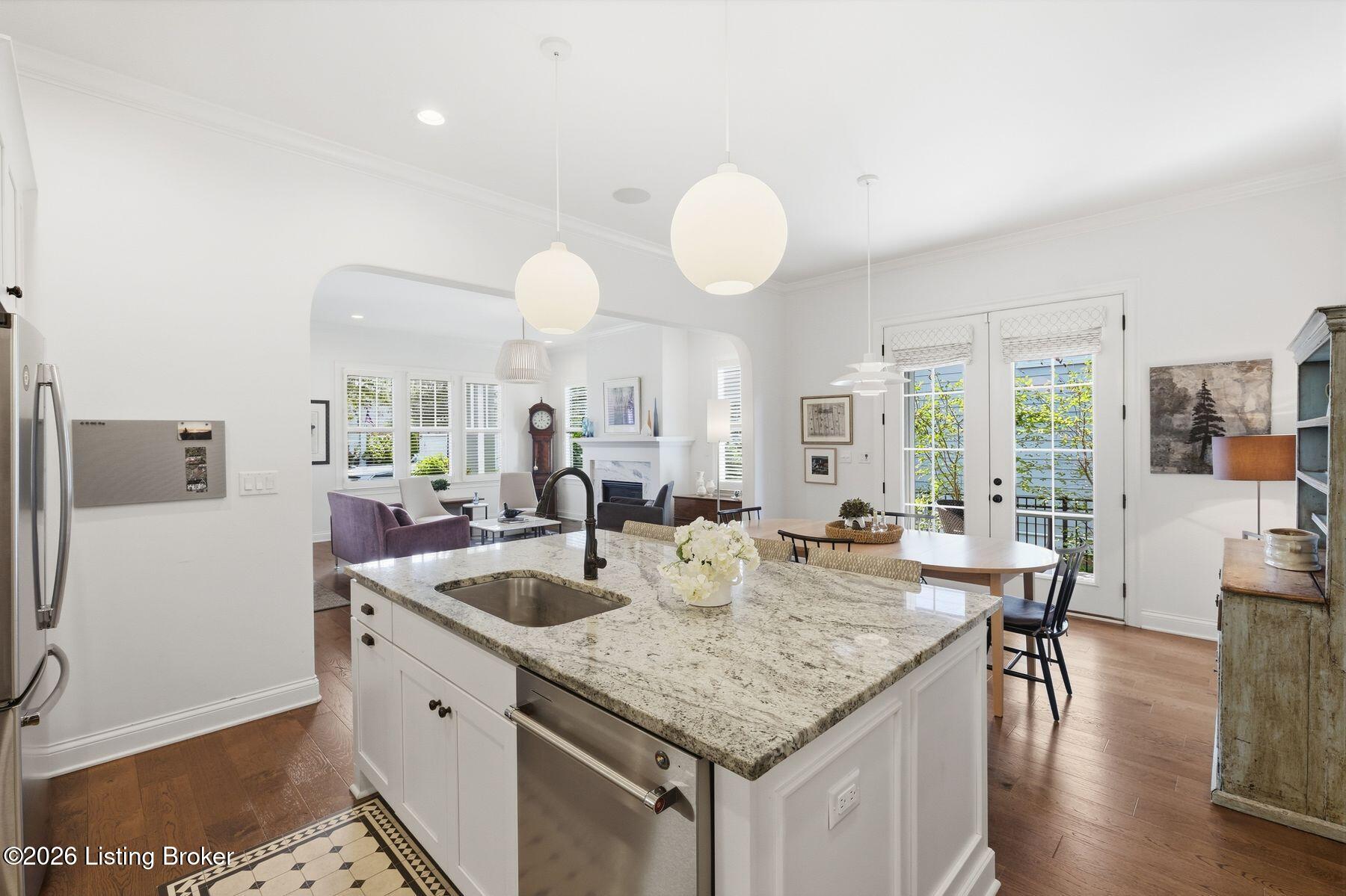 Open-plan kitchen with a large granite island, stainless steel appliances, and French doors to a balcony.